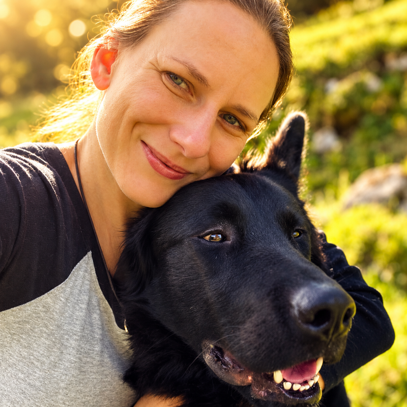 Sabrina Porsch mit ihrem schwarzen Hund im Gras
